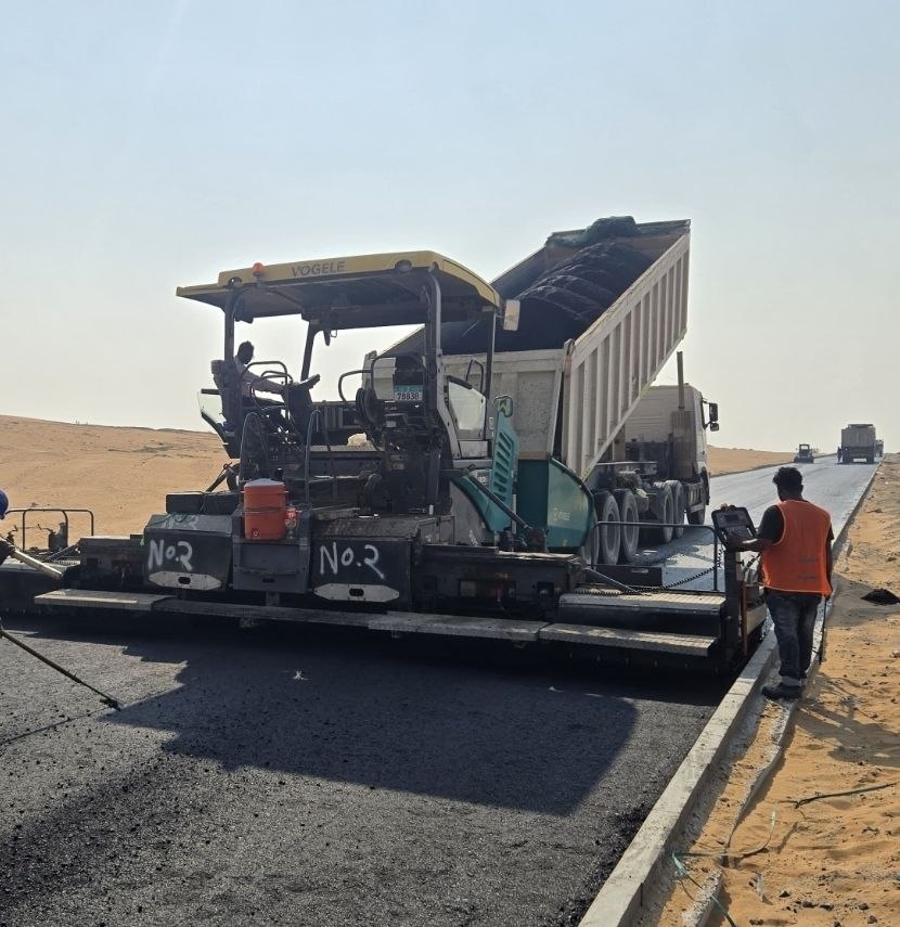 Asphalt paving machine and tipping truck laying a road